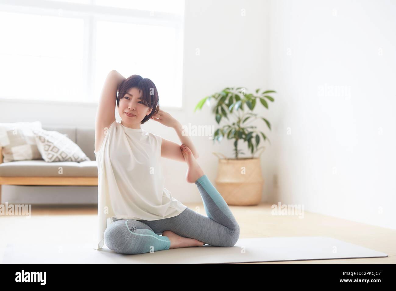 Donna che fa yoga posa sul pavimento al coperto Foto Stock