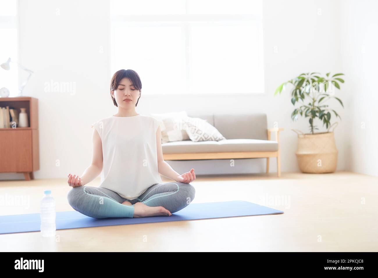 Donna che fa yoga posa sul pavimento al coperto Foto Stock