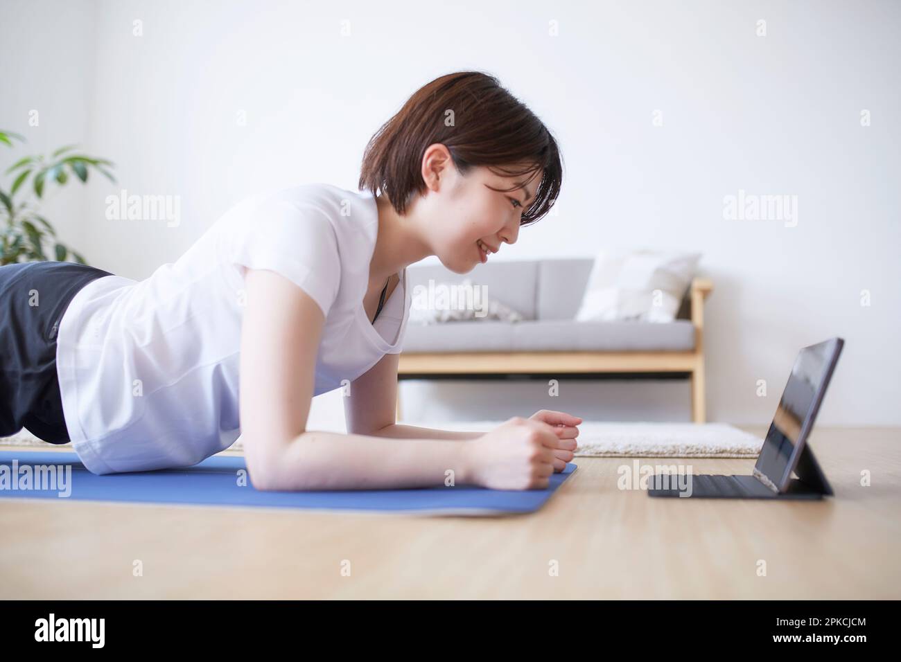 Donna che fa pose yoga mentre guarda un computer portatile sul pavimento Foto Stock