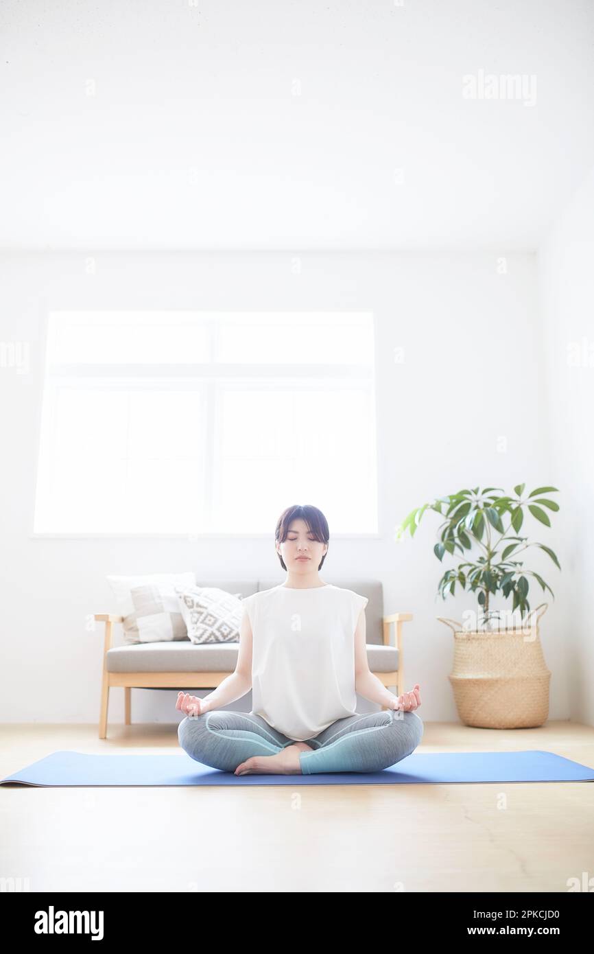 Donna che fa yoga posa sul pavimento al coperto Foto Stock