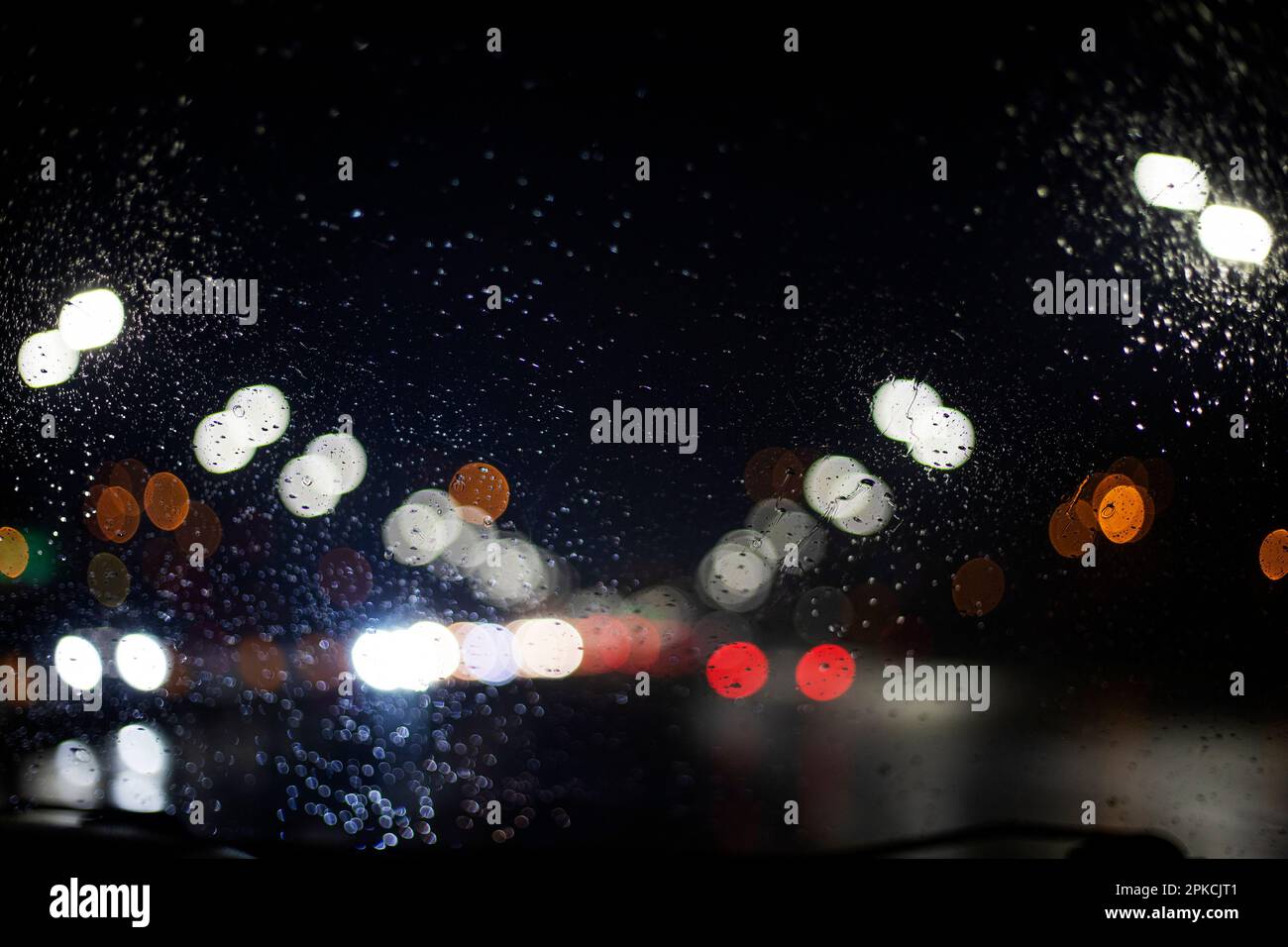 sfondo astratto da luci sfocate da fari su un parabrezza bagnato di un'auto in condizioni di maltempo. Blackout in Ucraina, Foto Stock