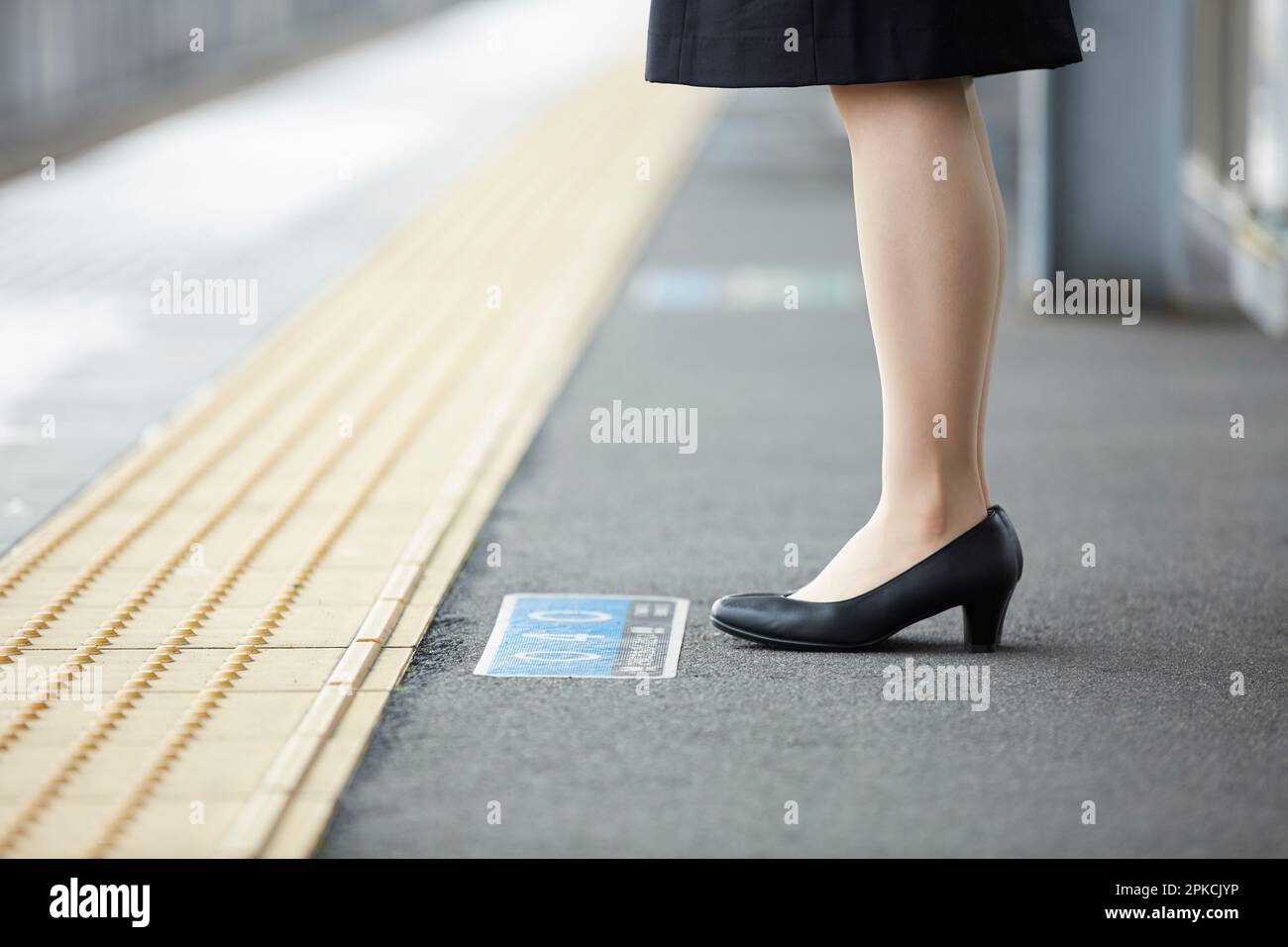 Donna in tuta in piedi sulla piattaforma della stazione Foto Stock