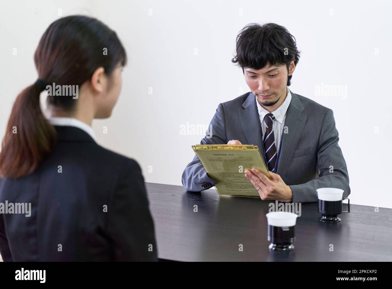 Un intervistatore maschile intervistando un cacciatore di lavoro femminile e scrivendo informazioni su un documento. Foto Stock