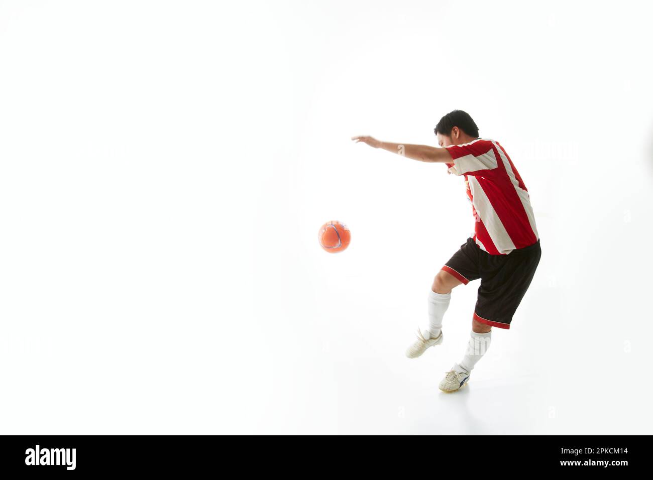 Giocatore di calcio che cerca di calciare il pallone Foto Stock