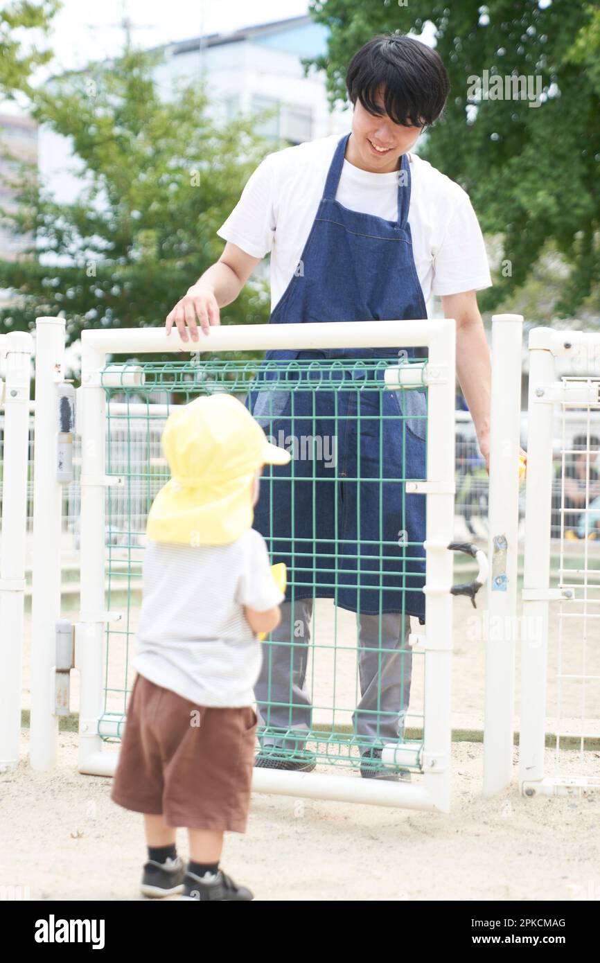 Assistente di assistenza all'infanzia e bambino che aprono la porta della sandbox Foto Stock
