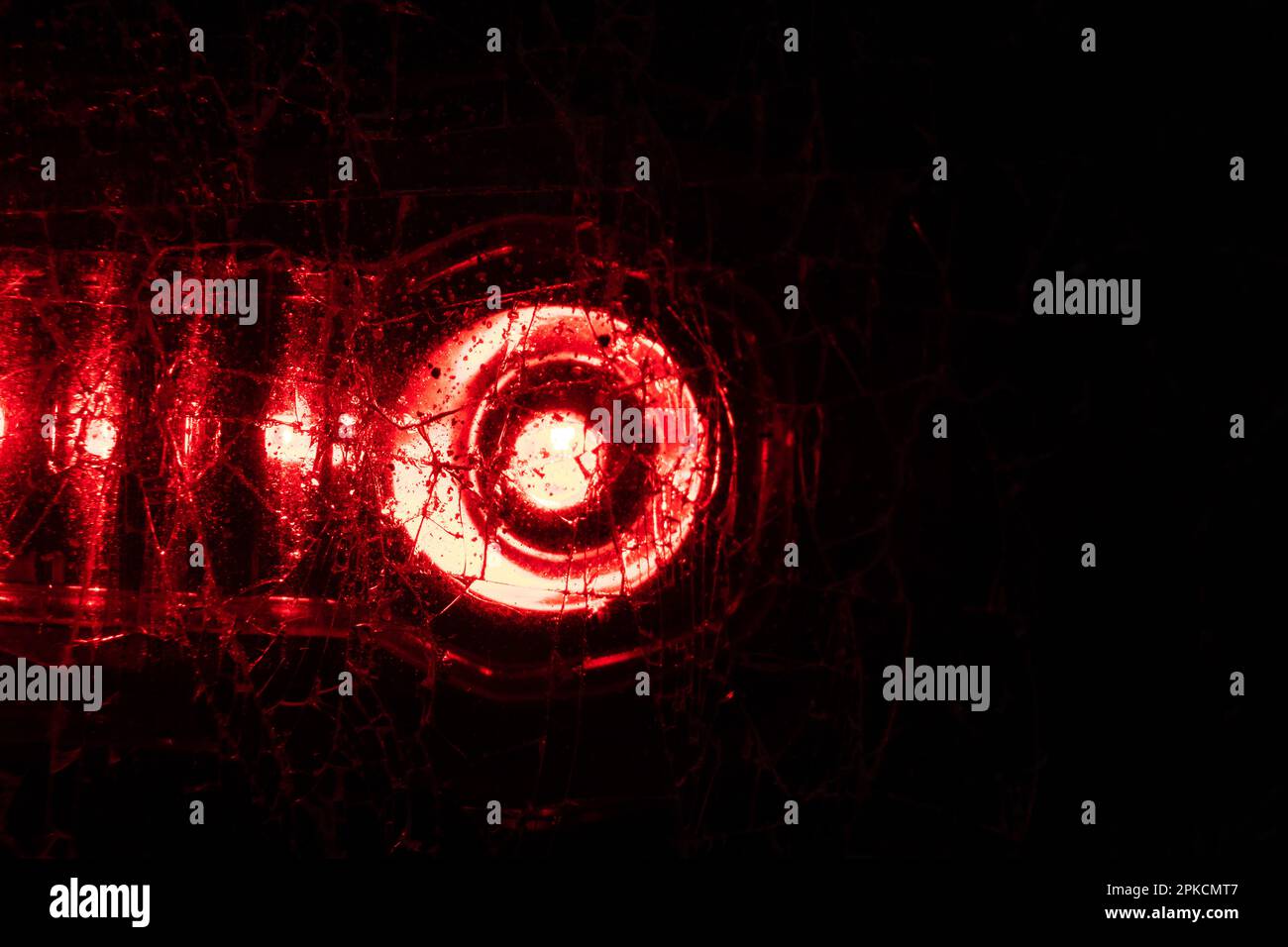 la luce di una lanterna rossa splende attraverso la macro foto di vetro spezzata come sfondo Foto Stock