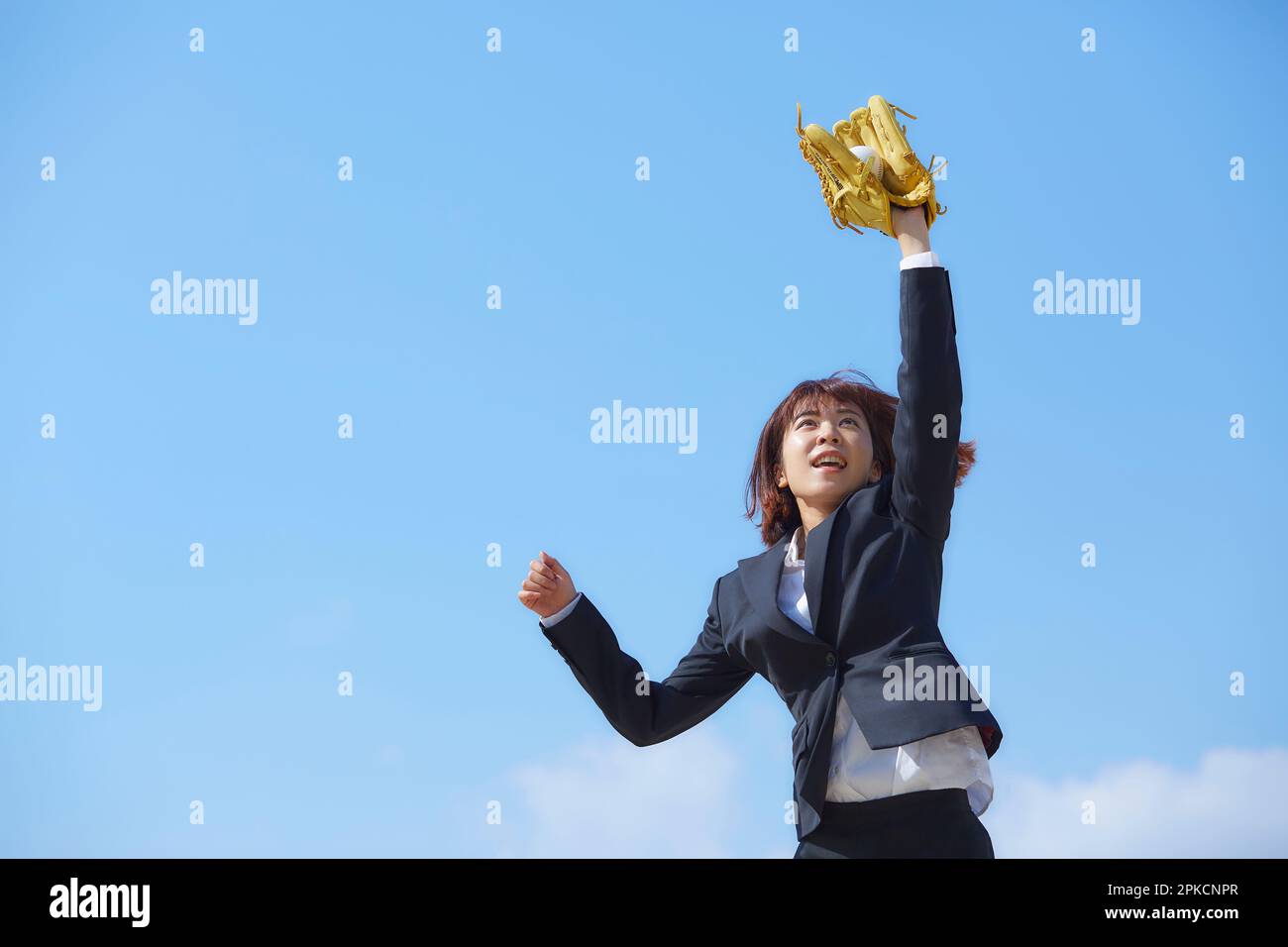 Donna in tuta che si allunga con un guanto sotto il cielo blu Foto Stock
