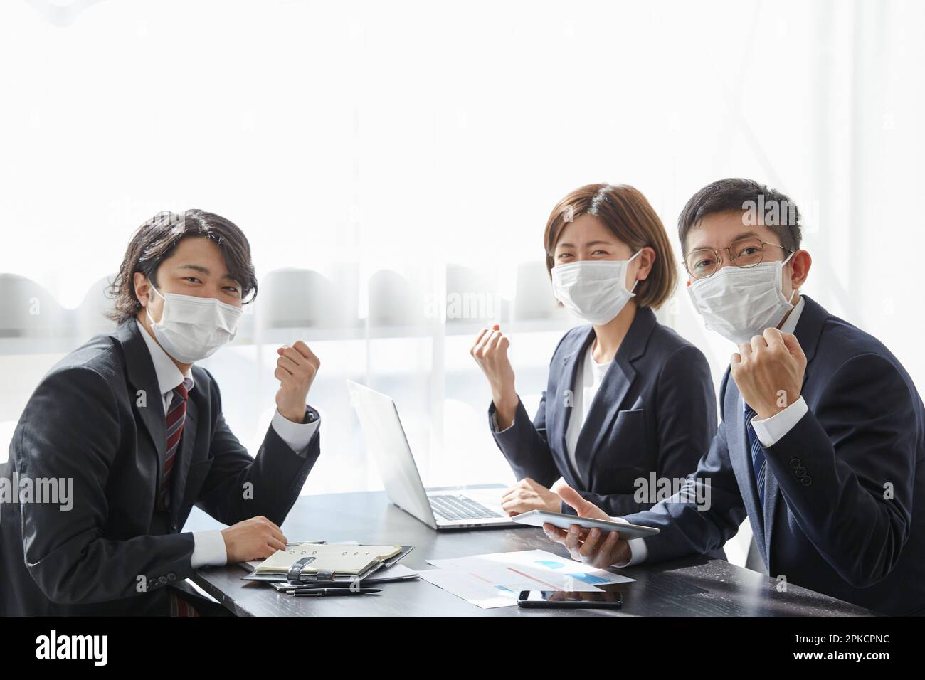 Tre impiegati che indossano maschere in ufficio Foto Stock