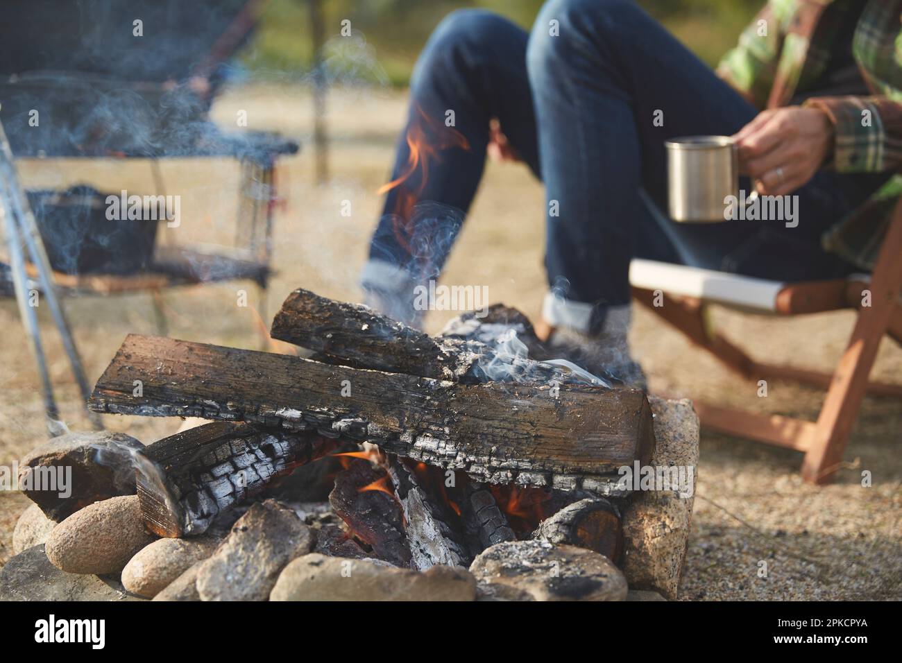 Un uomo che si riscalda da un fuoco Foto Stock