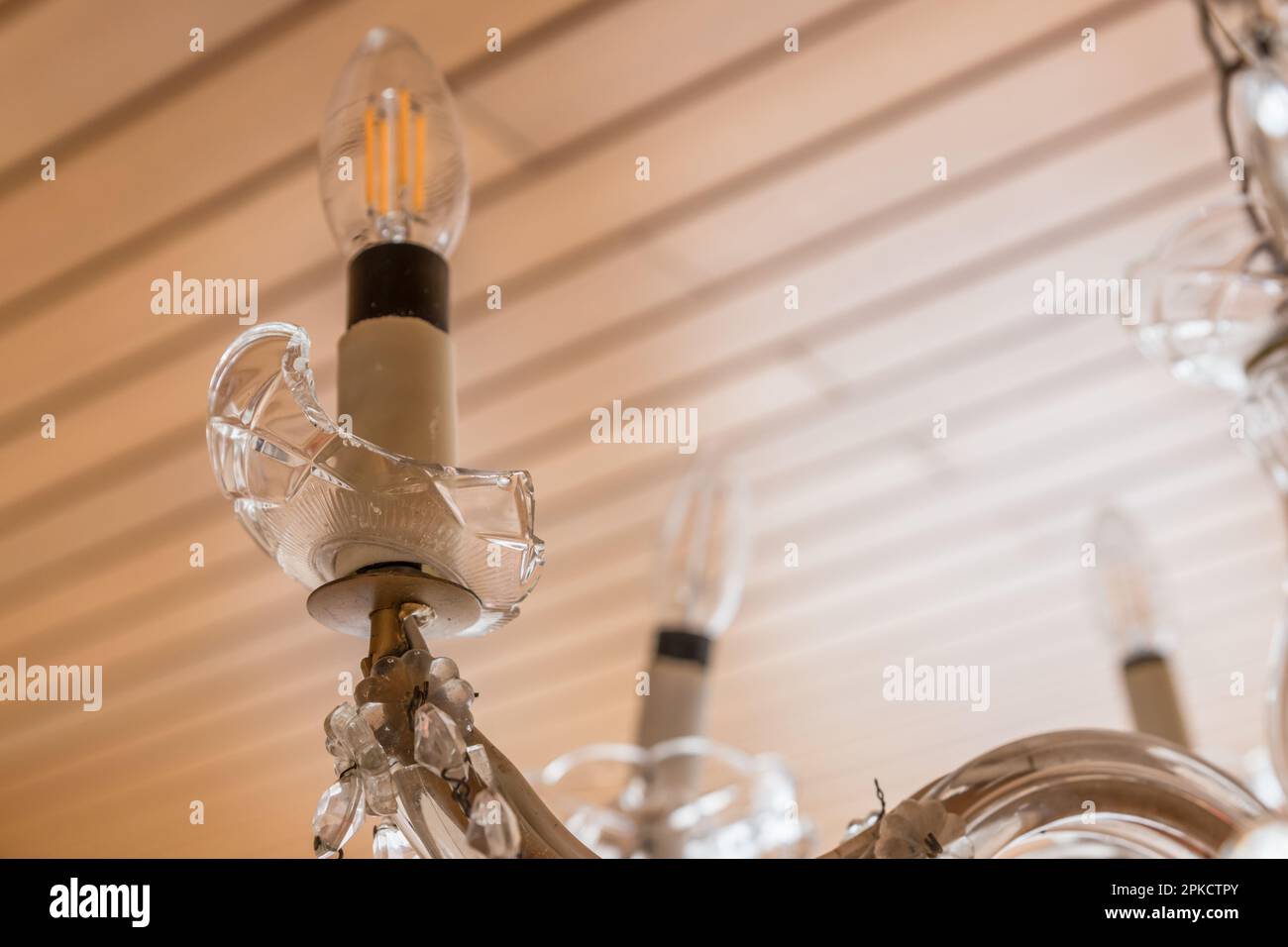 Lampadario di vetro rotto nel soggiorno con un braccio di luce rotto con una lampadina, Germania Foto Stock