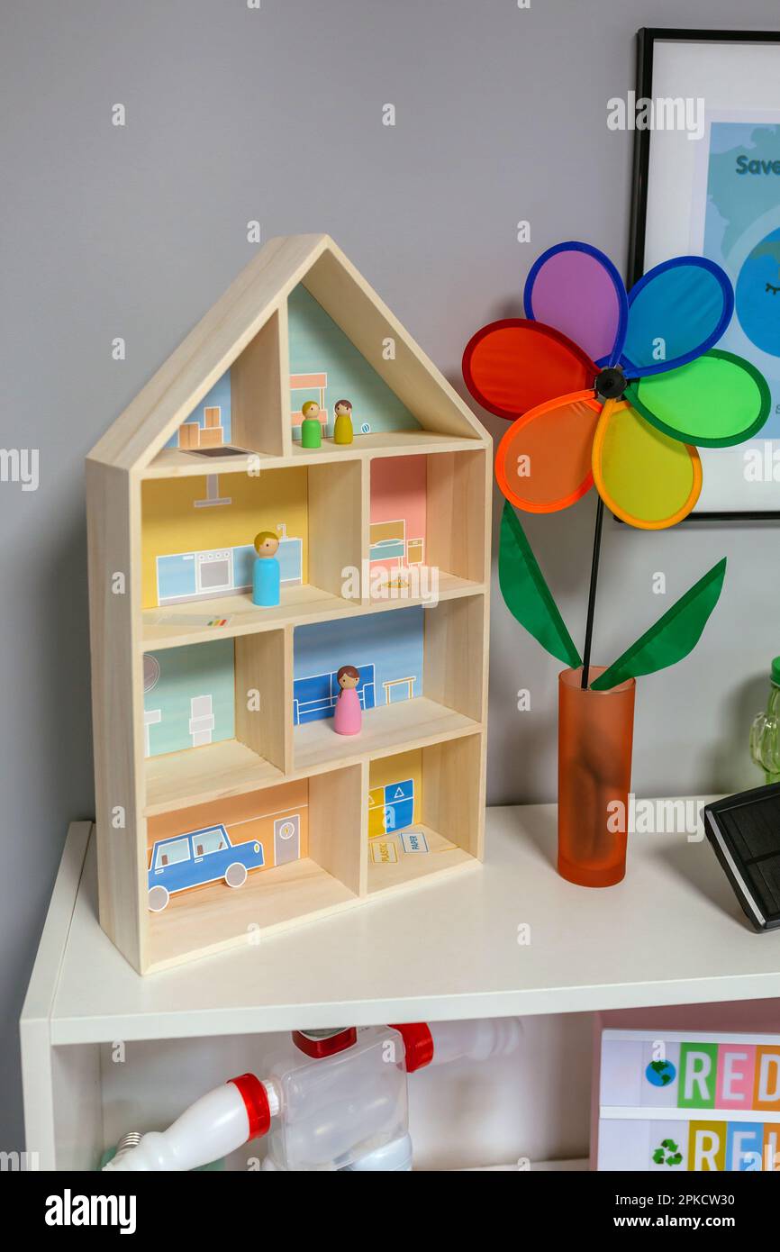 Primo piano del modello di casa sostenibile e della rotella colorata sopra lo scaffale nella classe ambientale. Concetto di educazione ecologica. Foto Stock