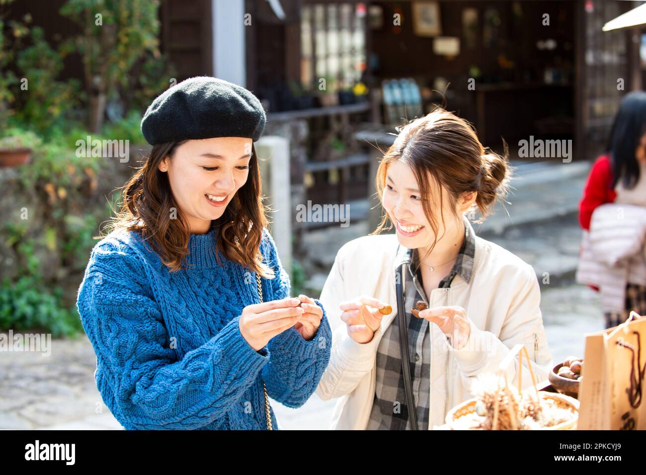 Due donne mangiano castagne in un negozio in un luogo turistico Foto Stock