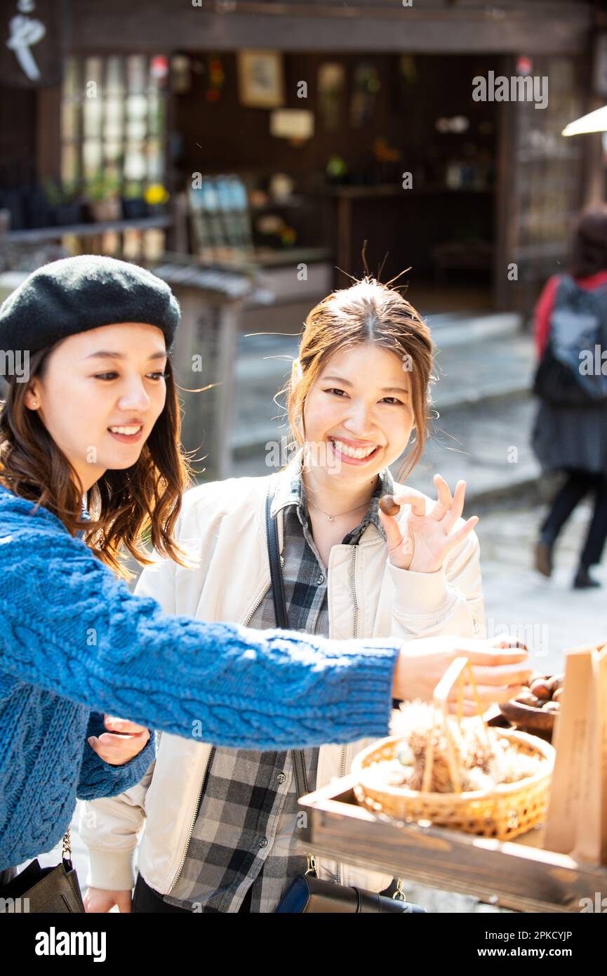 Due donne mangiano castagne in un negozio in un luogo turistico Foto Stock