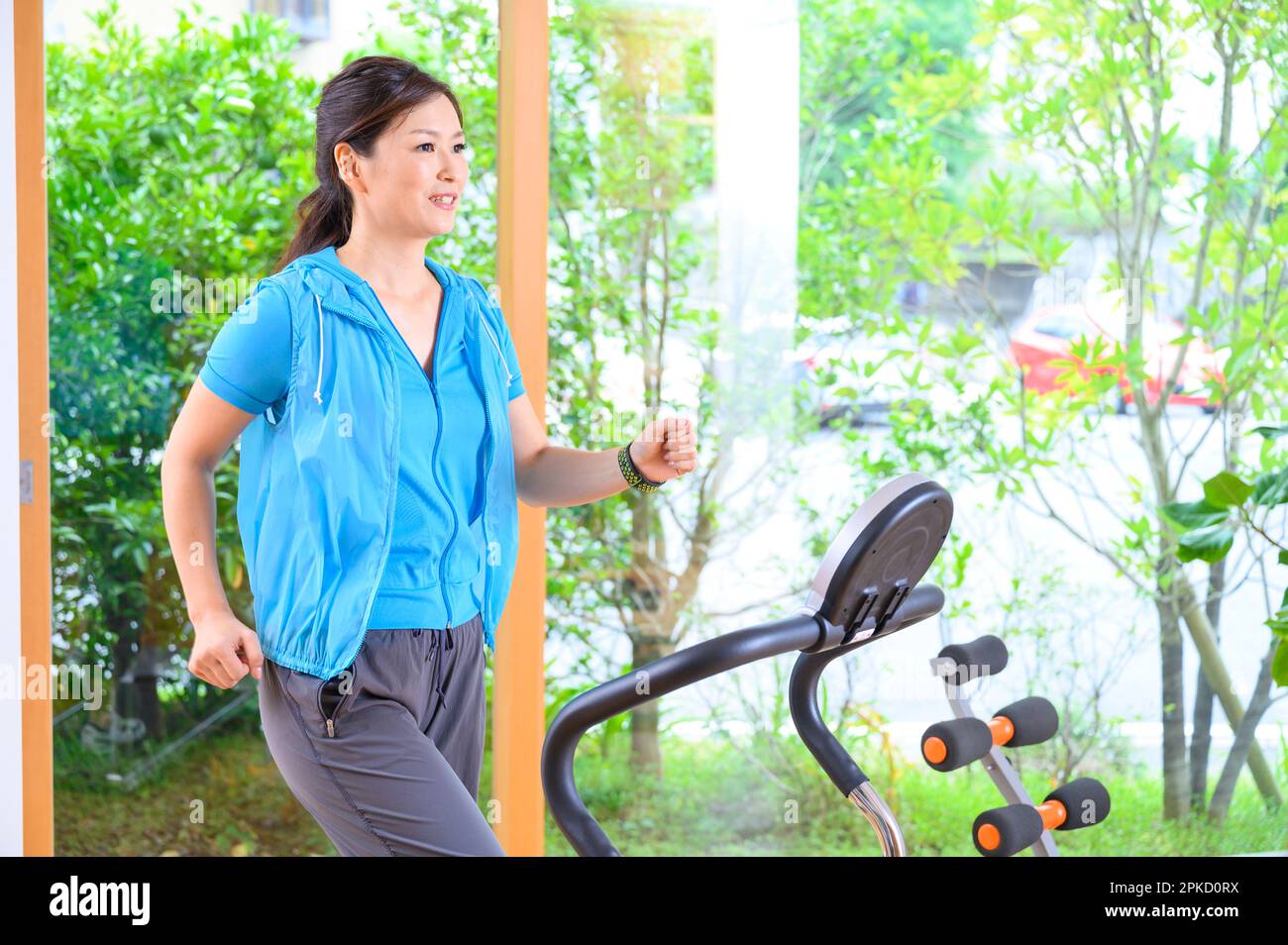 Una donna di mezza età che si esercita con una macchina nella sua casa Foto Stock