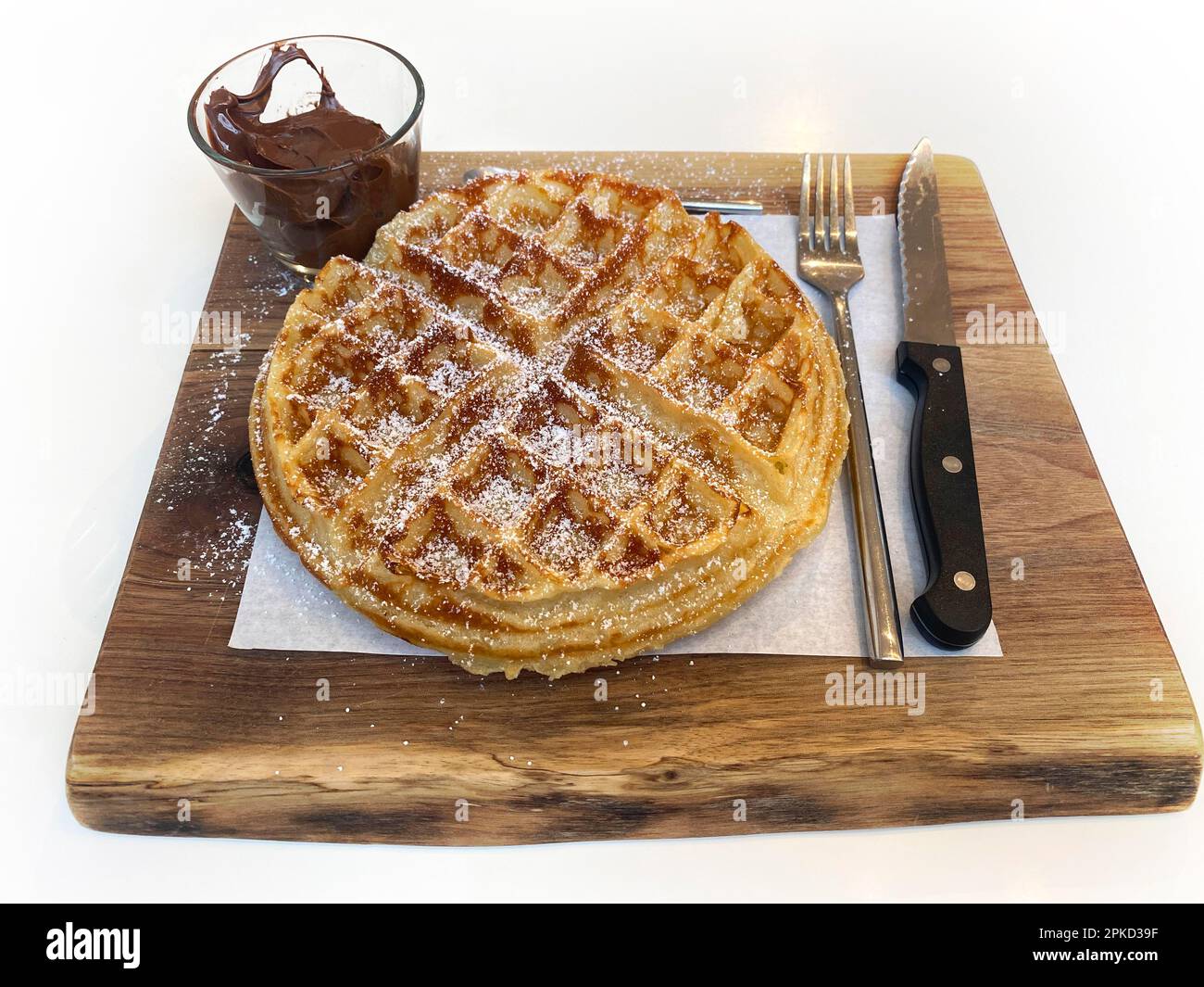Waffle belgi con zucchero a velo, crema al cioccolato Nutella, posate, su asse di legno, Stoccarda, Baden-Wuerttemberg, Germania Foto Stock