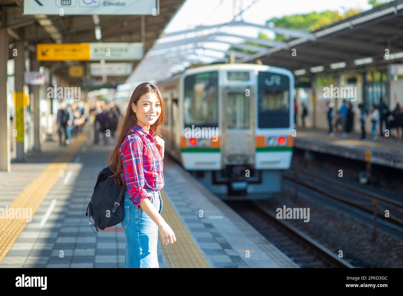 Donna su una piattaforma ferroviaria in attesa di un treno Foto Stock