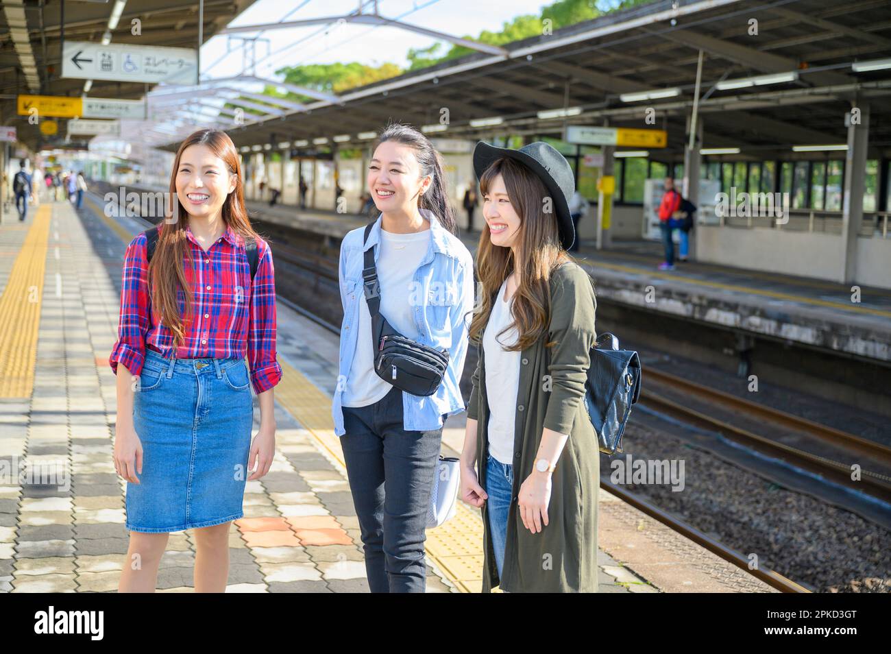 3 donne in attesa del treno al binario della stazione Foto Stock
