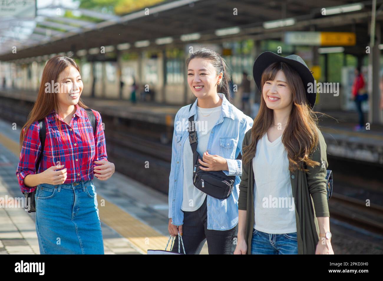 3 donne in attesa del treno al binario della stazione Foto Stock