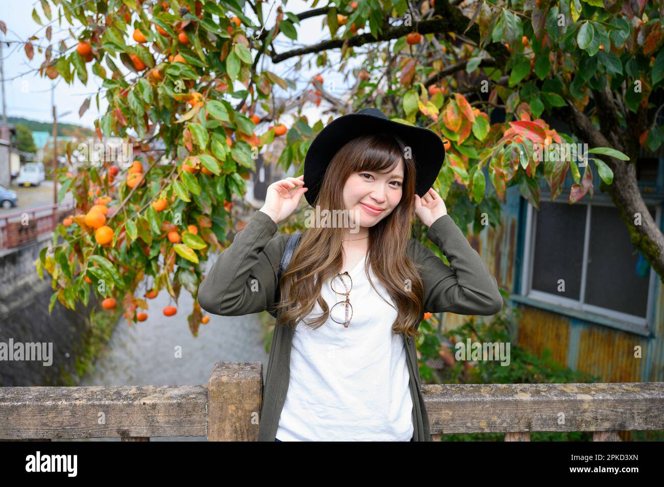 Donna sorridente davanti ad un ruscello e ad un albero di persimmon Foto Stock