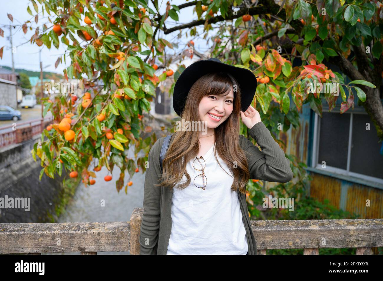 Donna sorridente davanti ad un ruscello e ad un albero di persimmon Foto Stock