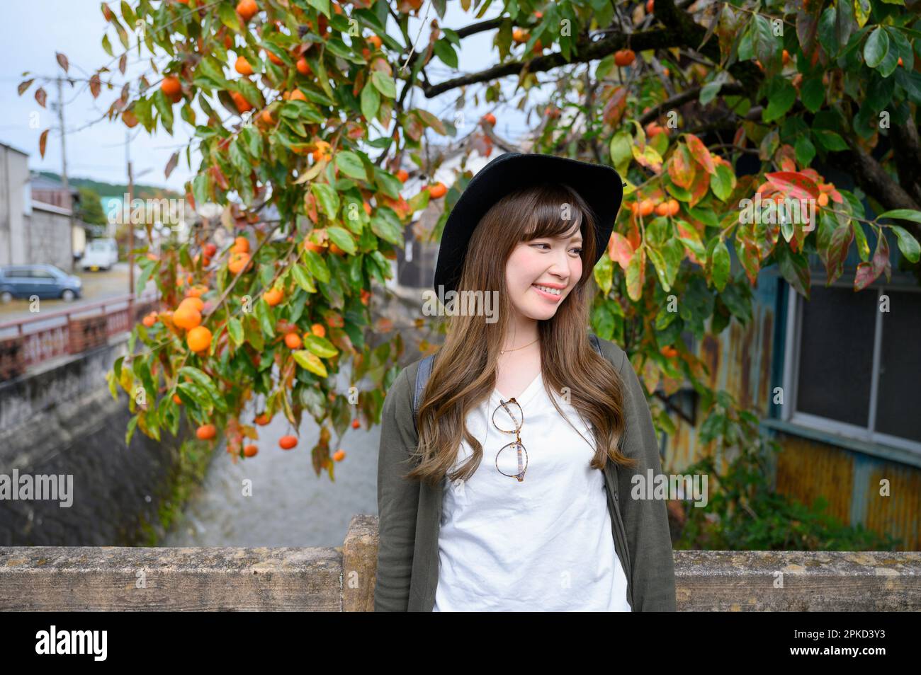 Una donna sorridente davanti ad un ruscello e ad un albero di persimmon Foto Stock