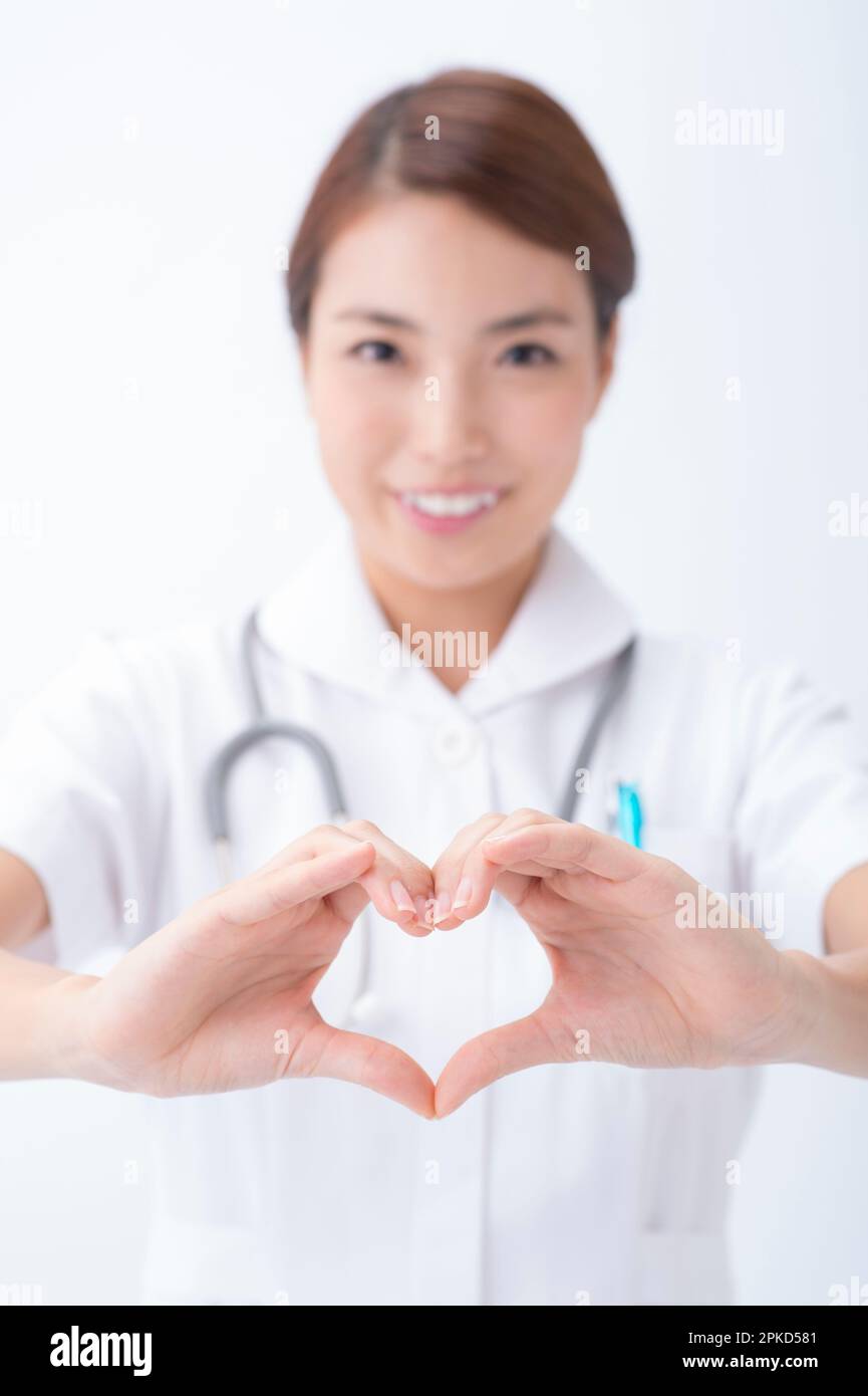 Infermiera che fa il simbolo del cuore con la mano Foto Stock