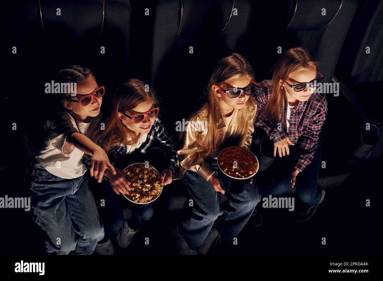 Amici che guardano film insieme. Gruppo di bambini seduti al cinema Foto Stock