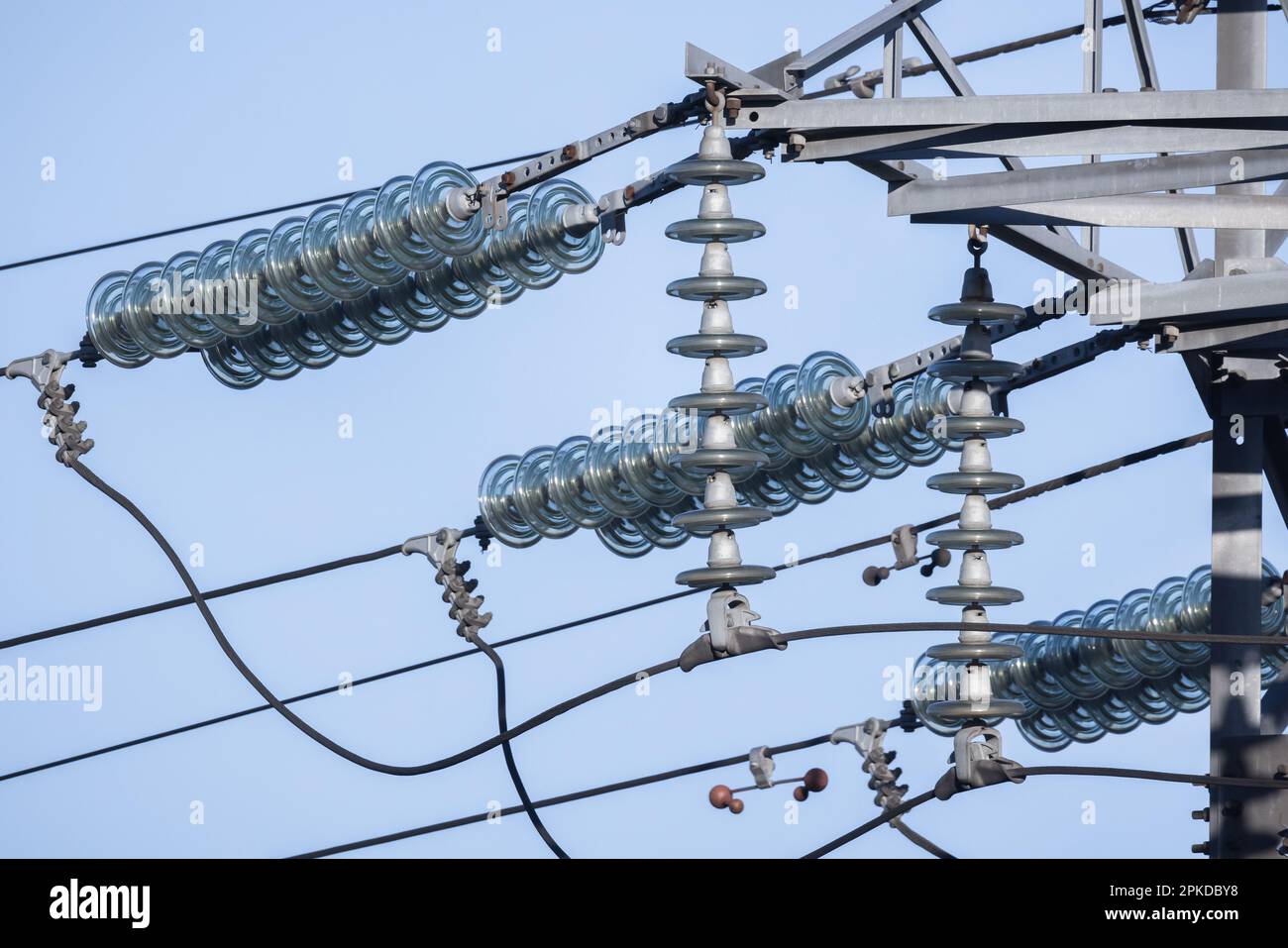 Gli isolatori ad alta tensione della linea elettrica aerea sono sotto il cielo blu durante il giorno Foto Stock