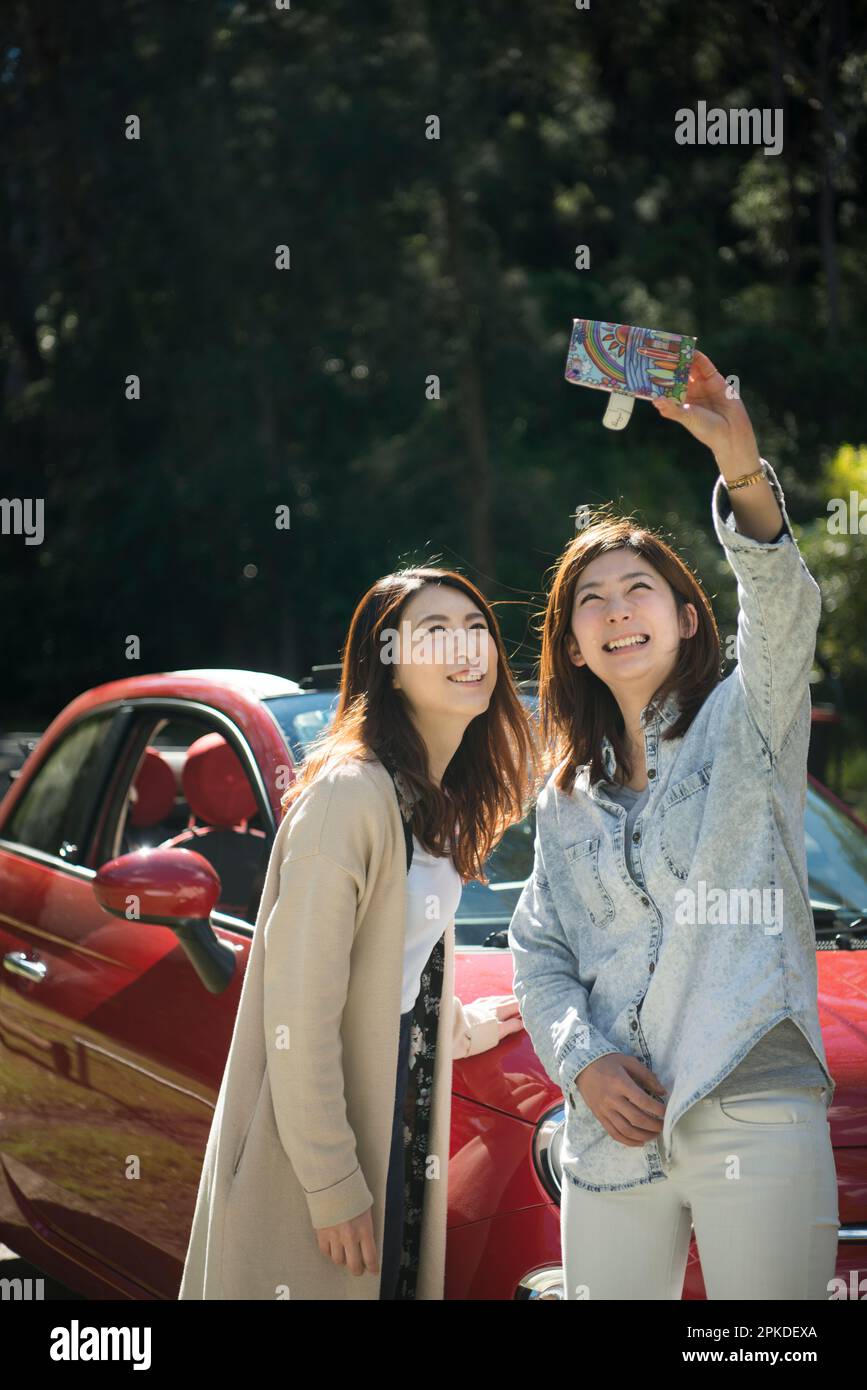 2 donne che scattano una foto davanti ad un'auto Foto Stock