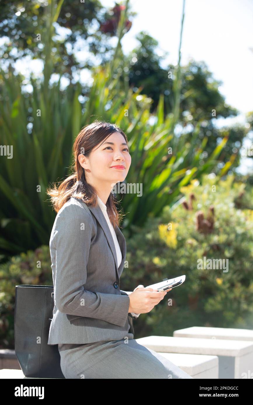 Donna in tuta che tiene il telefono e guarda lontano Foto Stock