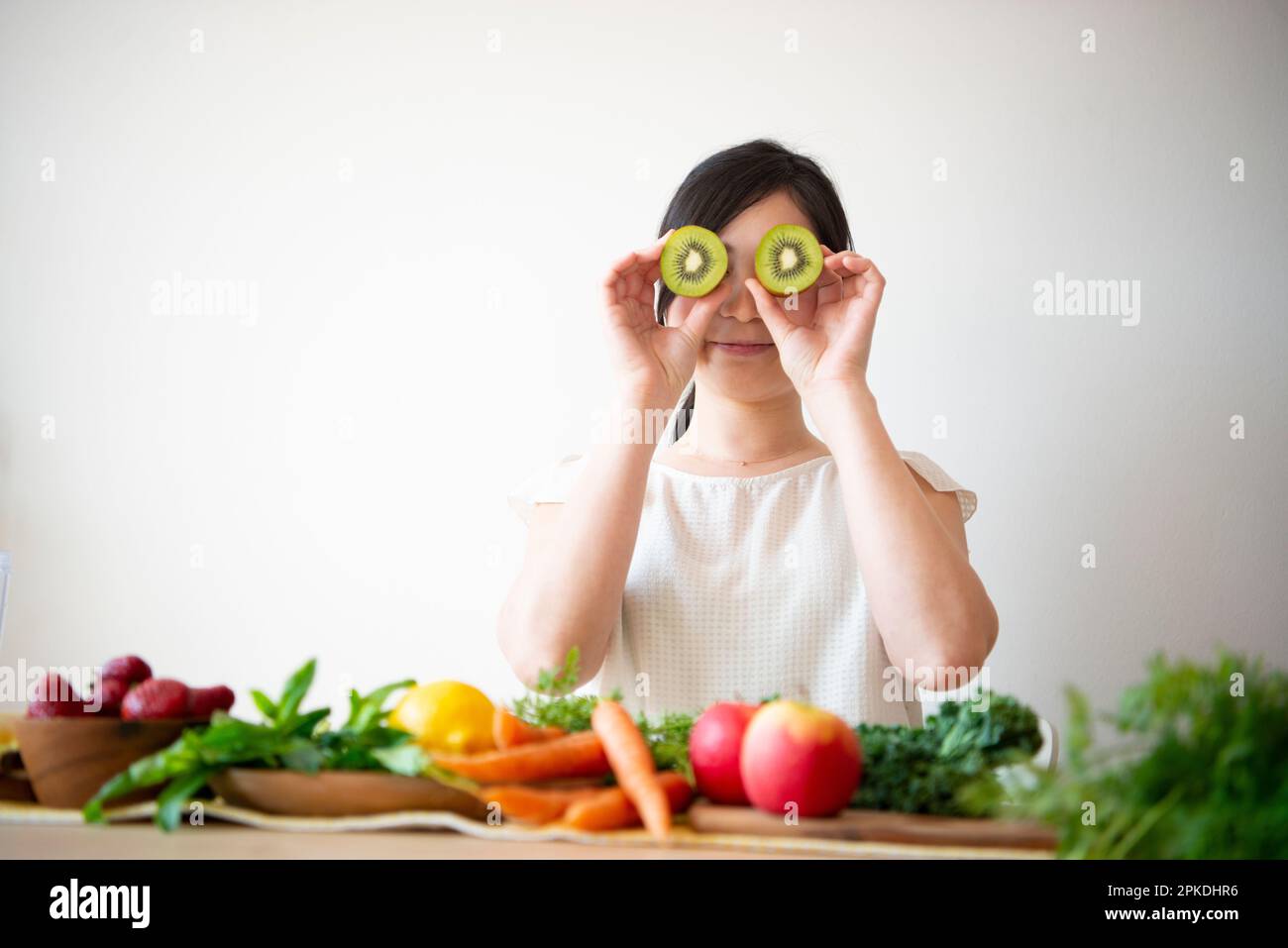 Donna che tiene kiwi a livello degli occhi Foto Stock