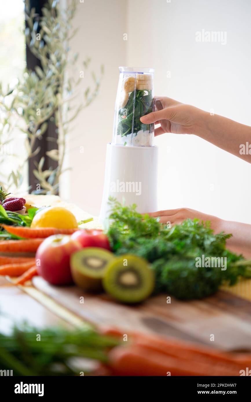 Donna che carica gli ingredienti per un frullato in un frullatore Foto Stock