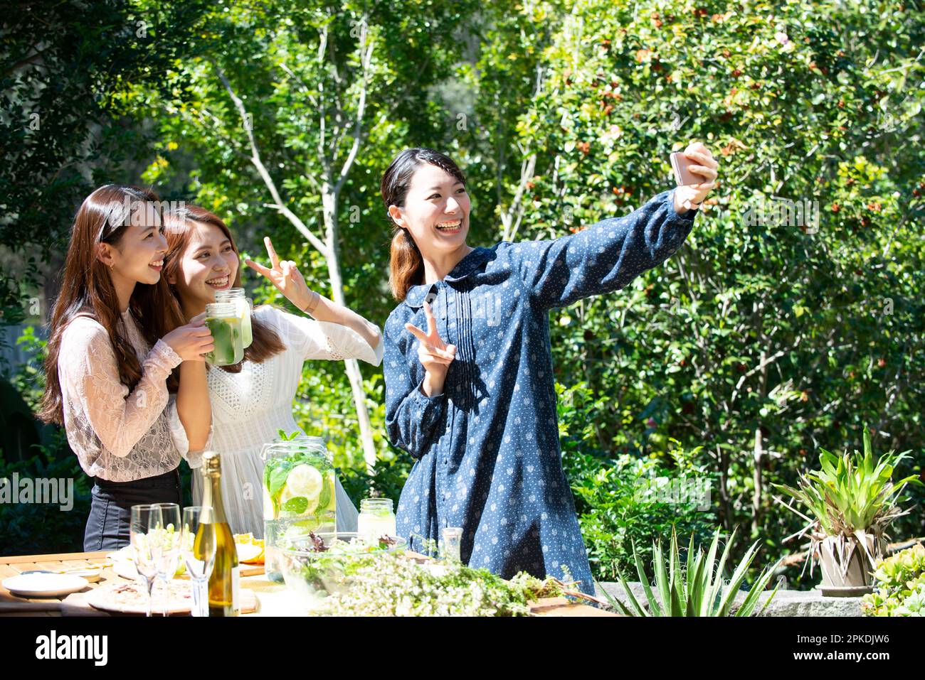 Tre donne sorridenti che scattano selfie a una festa in giardino Foto Stock