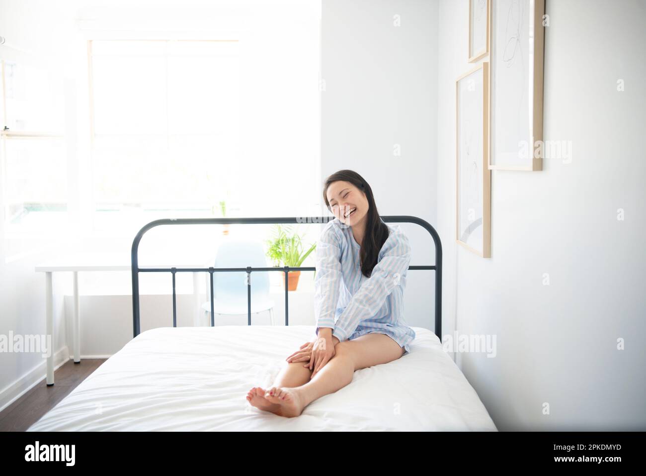 Donna in pigiama seduta sul letto Foto Stock