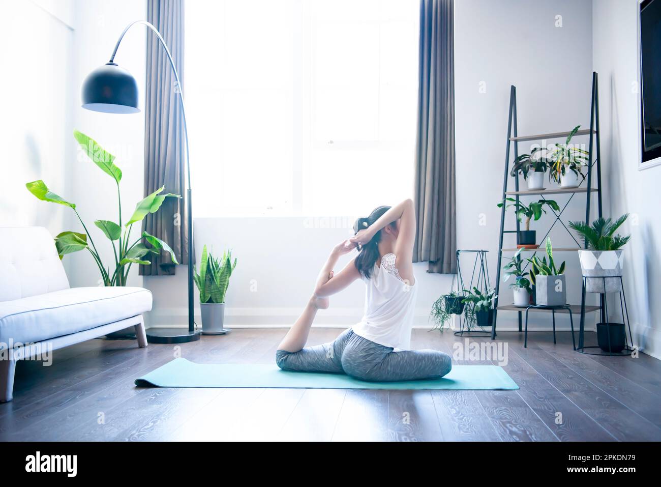 Donna che fa yoga nel soggiorno di una casa Foto Stock