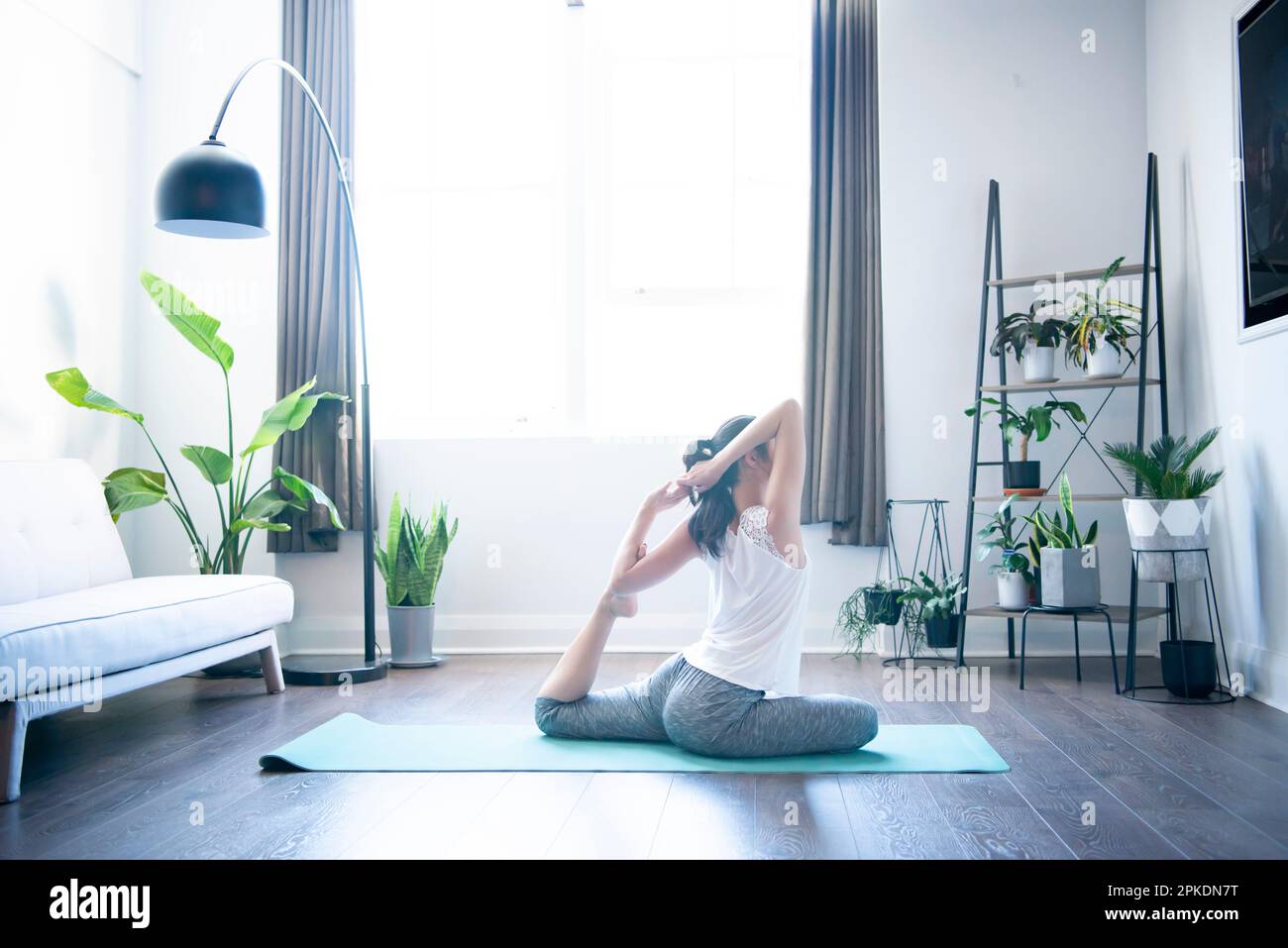 Donna che fa yoga nel soggiorno di una casa Foto Stock