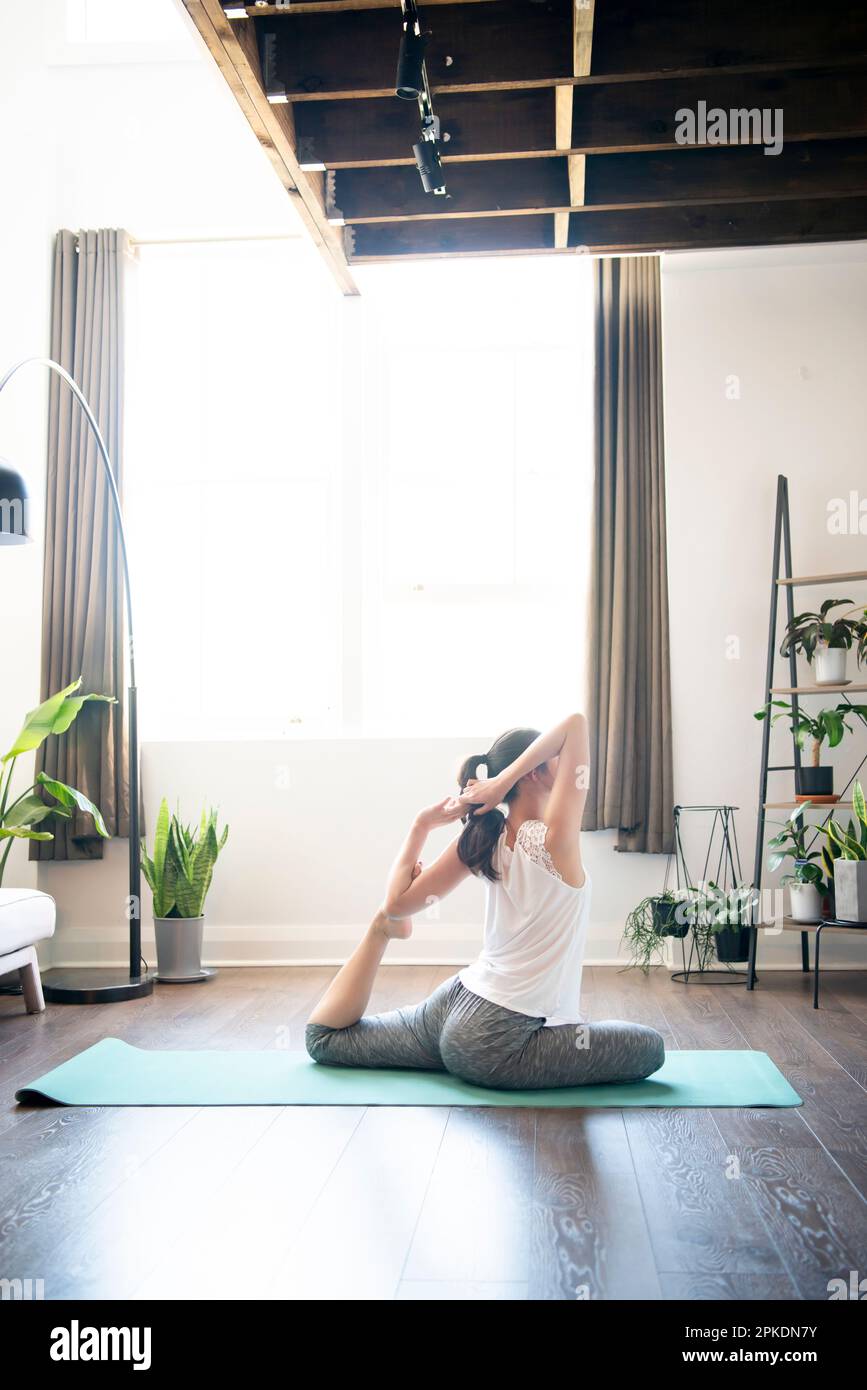 Donna che fa yoga nel soggiorno di una casa Foto Stock