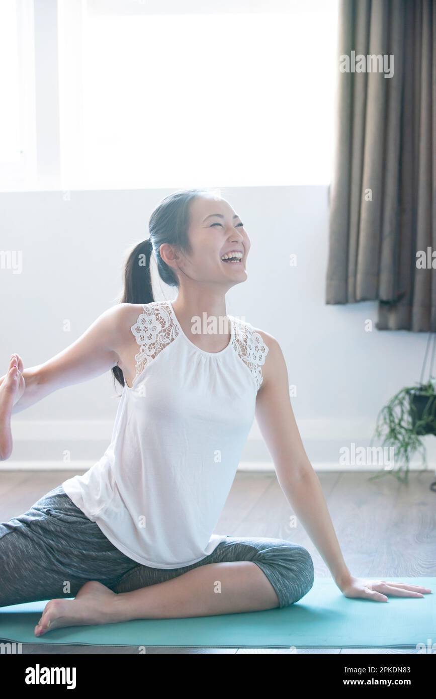 Donna che fa yoga nel soggiorno di una casa Foto Stock