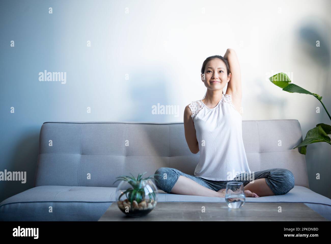 Donna seduta sul divano soggiorno stretching Foto Stock