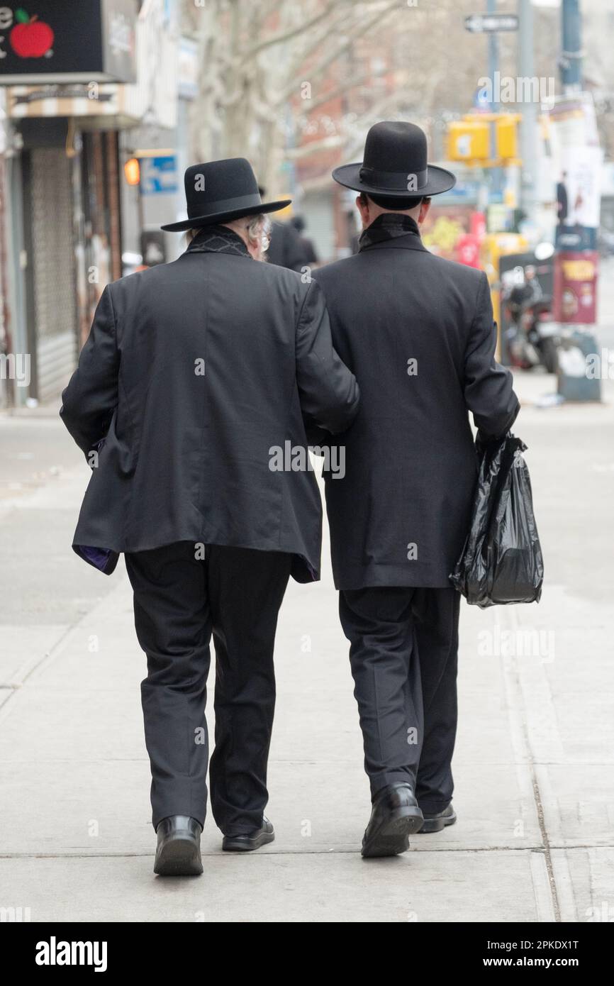 Due uomini ebrei anonimi camminano insieme braccio in braccio per il sostegno. A Brooklyn, New York. Foto Stock