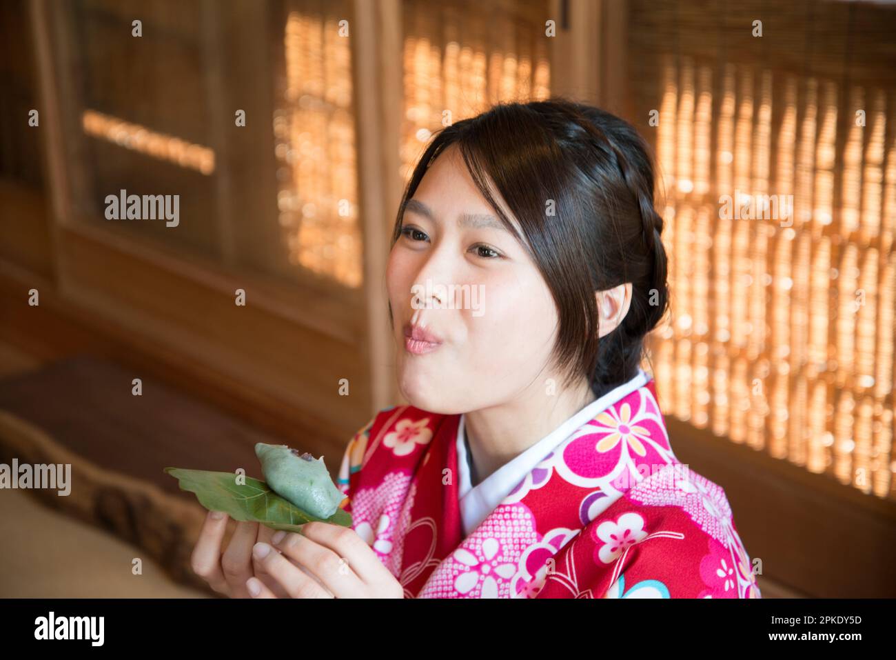 Donna in Kimono che mangia Kashiwa Mochi Foto Stock