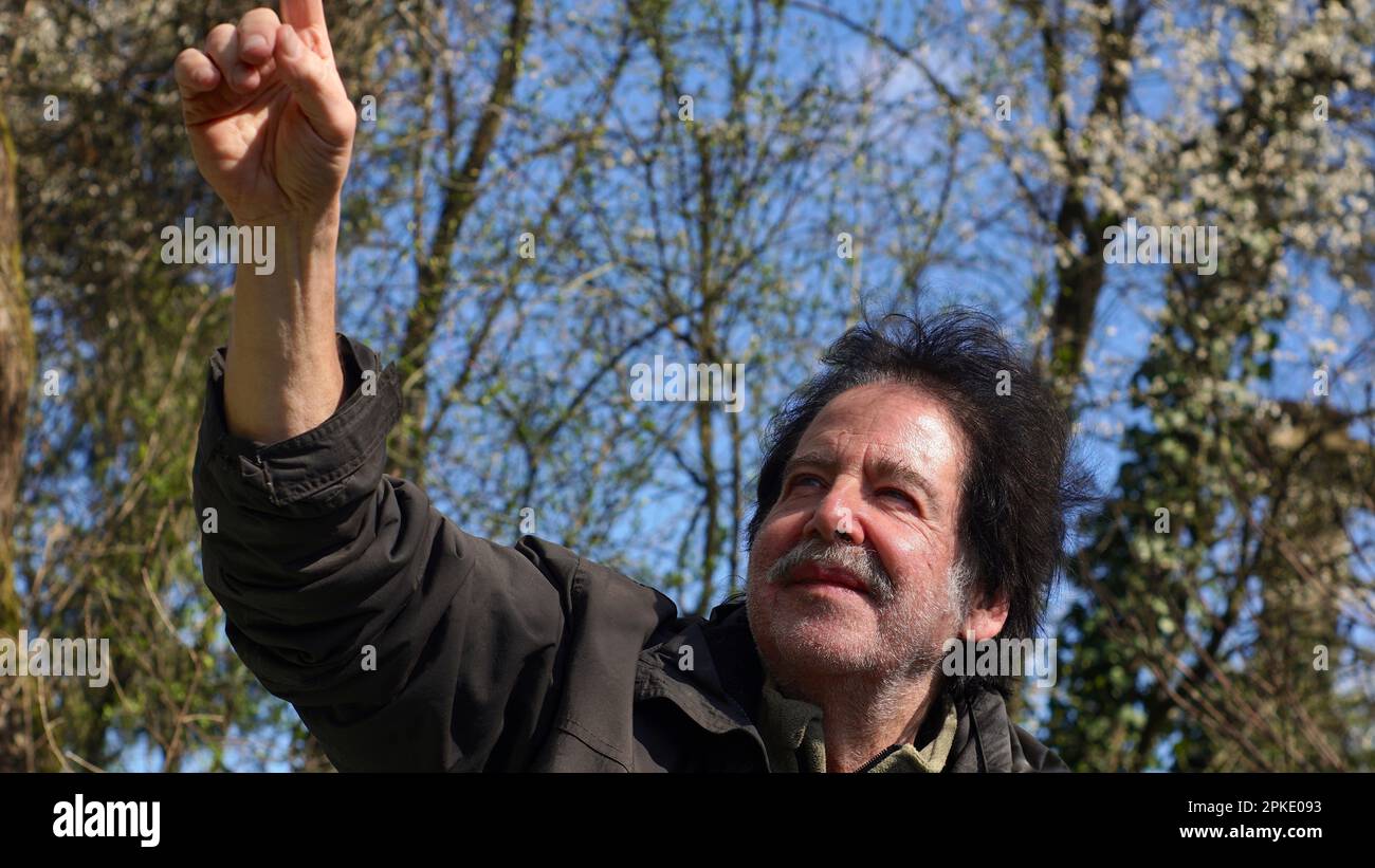 Un uomo sorridente che punta verso il cielo. Foto Stock