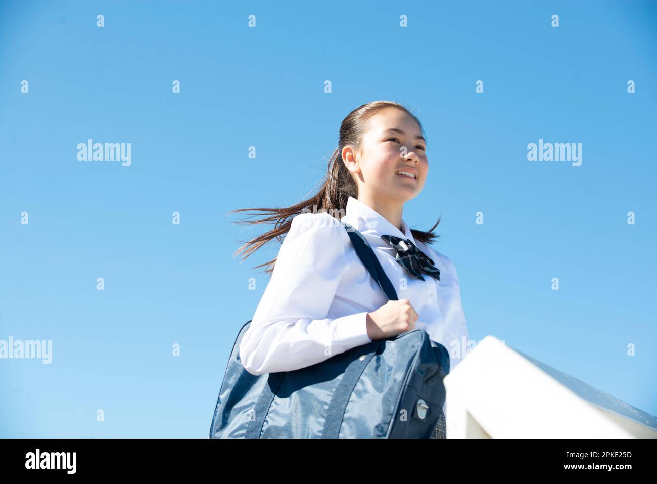 Studentessa in uniforme scolastica sorridente in lontananza Foto Stock