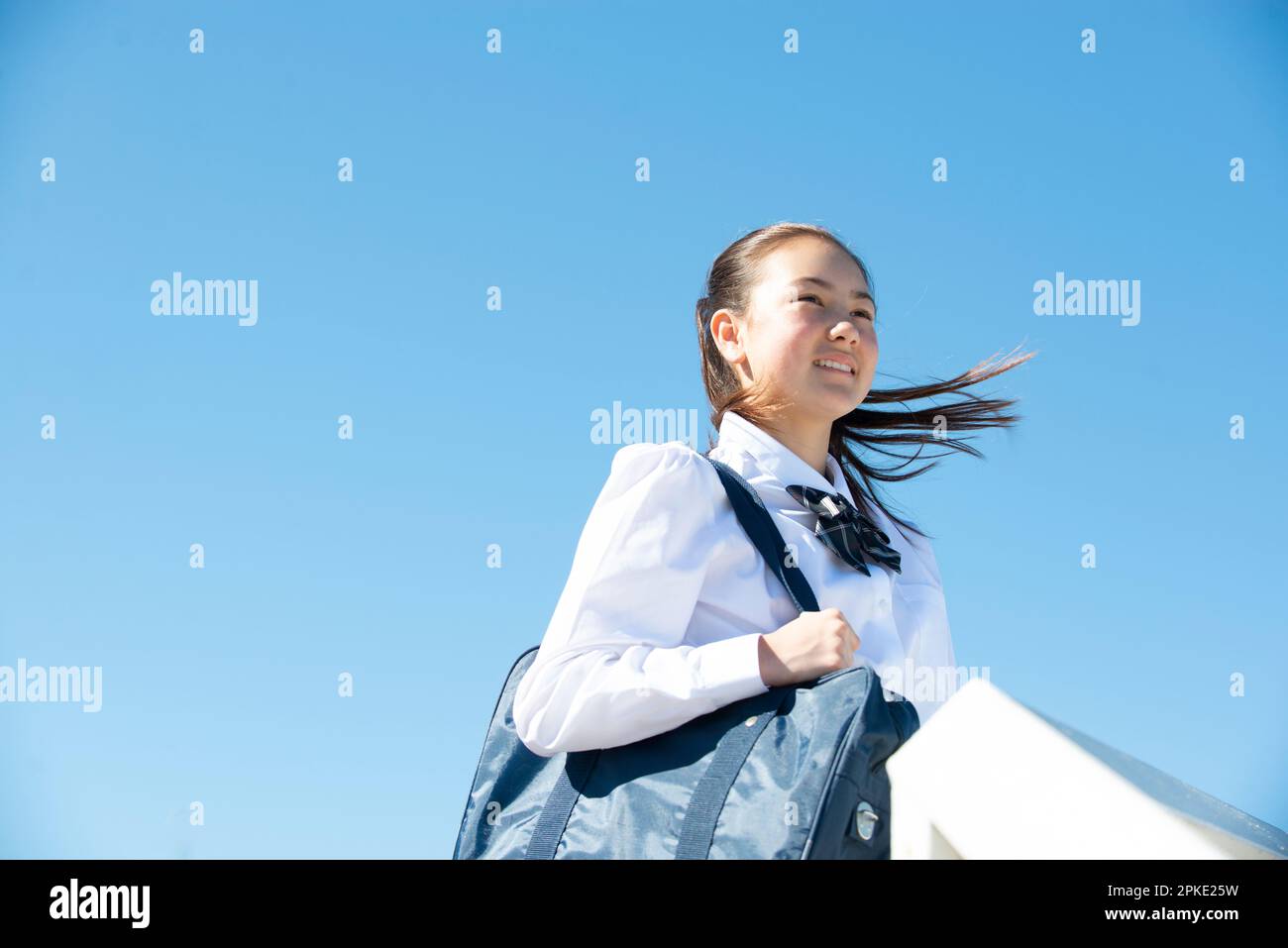 Studentessa in uniforme scolastica sorridente in lontananza Foto Stock