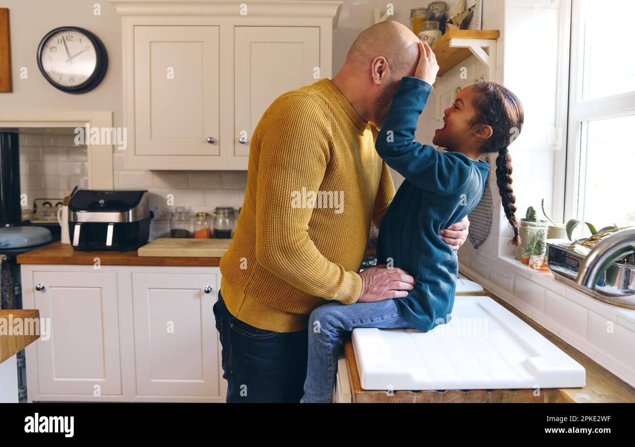 Padre e figlio giocoso con sindrome di Down sorridente in cucina Foto Stock