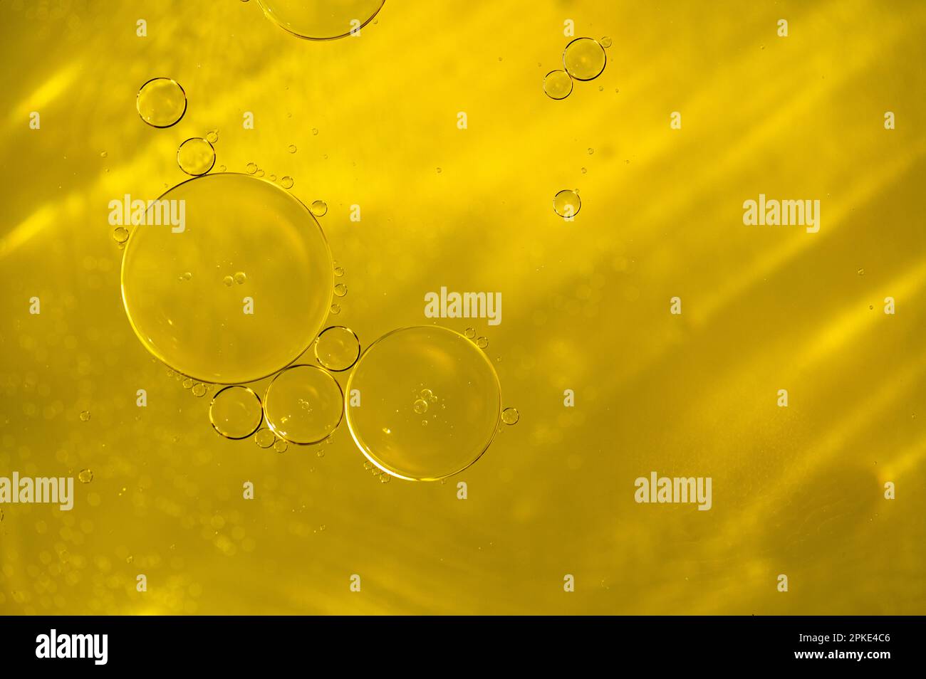 Primo piano di olio d'oro liquido, siero con bolle come struttura o sfondo Foto Stock