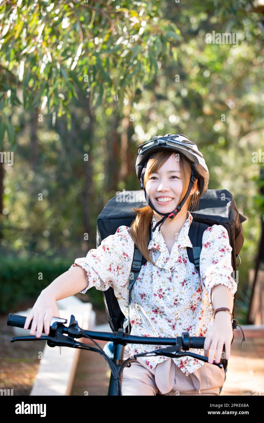 Donna consegna cibo uomo su una bicicletta Foto Stock
