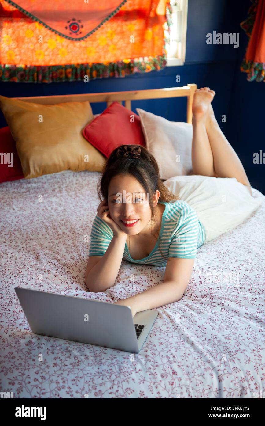 Donna che utilizza il computer a letto Foto Stock