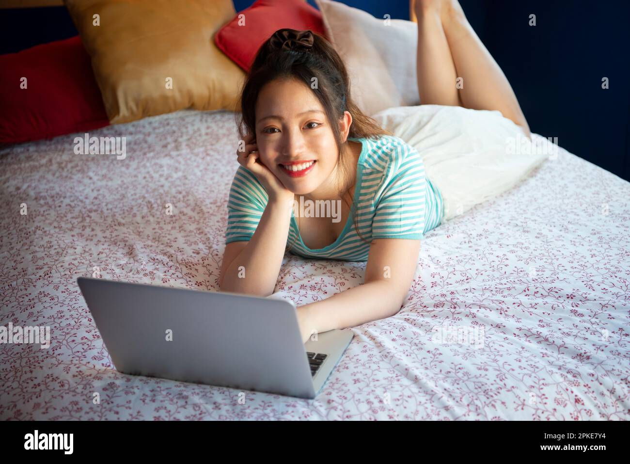 Donna che utilizza il computer a letto Foto Stock