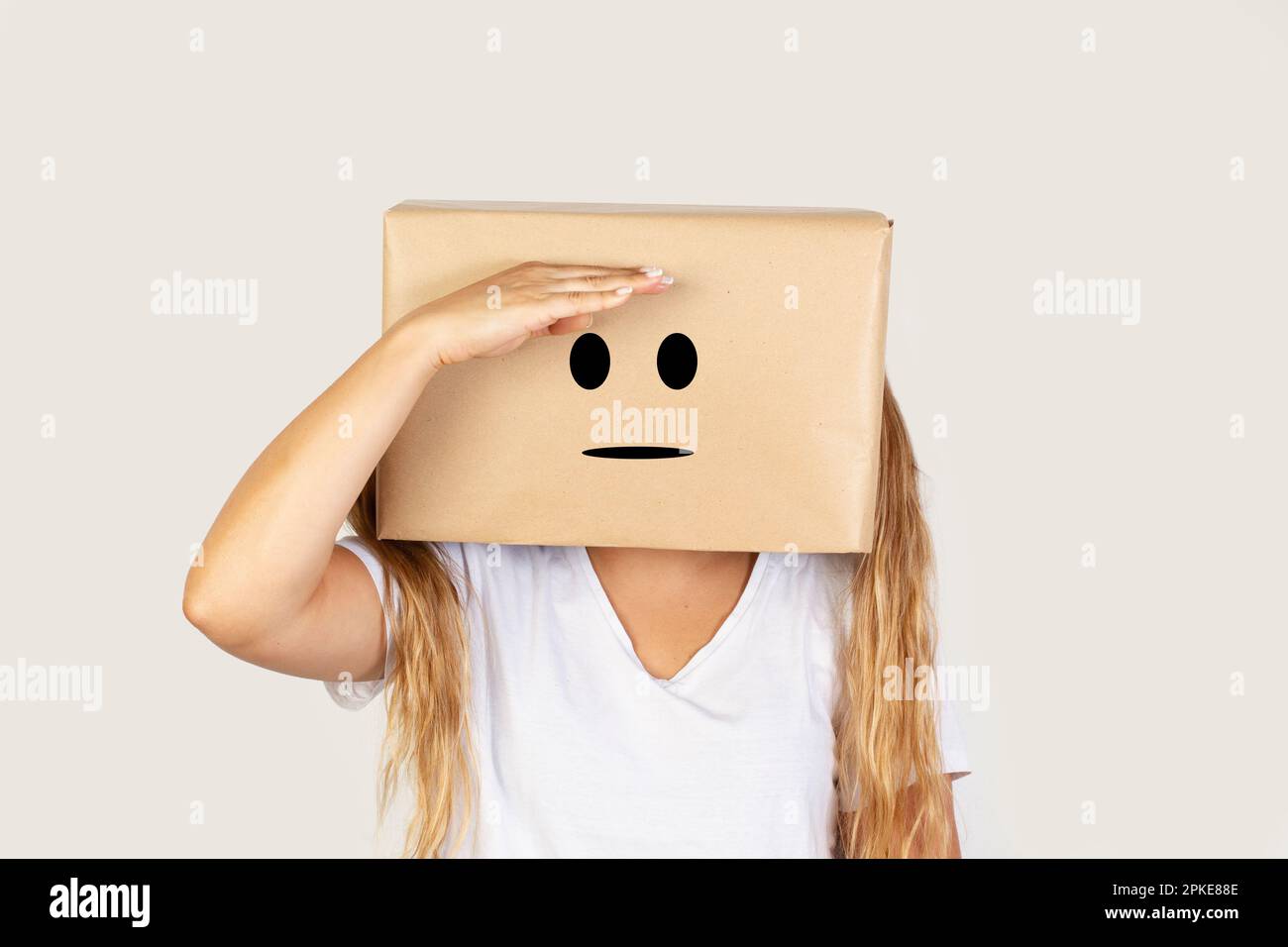 Donna con la testa in una scatola e gesto di ricerca in piedi su uno sfondo bianco con spazio copia Foto Stock